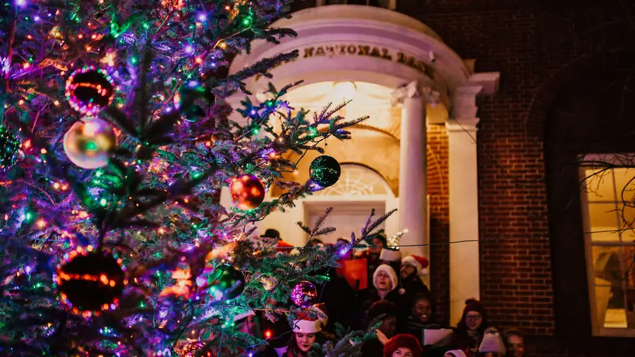 Carolers singing beside the lit Main Street Christmas tree